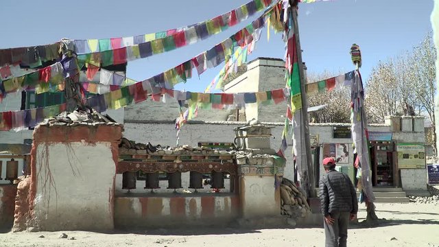A Nepal guy spinning prayer wheels, with prayer flags in the Himalaya.