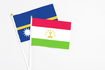 Tajikistan and Nauru stick flags on white background. High quality fabric, miniature national flag. Peaceful global concept.White floor for copy space.