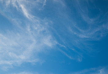 Fast moving clouds during a sunny day in the blue sky with the transition to evening hours along with the occasional flight of the aircraft leaving white traces on a flyby.