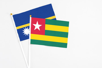 Togo and Nauru stick flags on white background. High quality fabric, miniature national flag. Peaceful global concept.White floor for copy space.