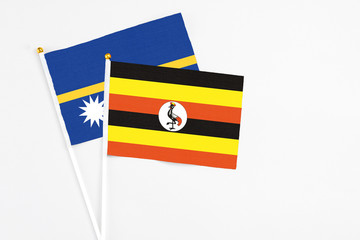 Fototapeta premium Uganda and Nauru stick flags on white background. High quality fabric, miniature national flag. Peaceful global concept.White floor for copy space.