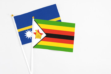 Zimbabwe and Nauru stick flags on white background. High quality fabric, miniature national flag....
