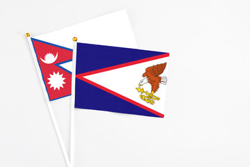American Samoa and Nepal stick flags on white background. High quality fabric, miniature national flag. Peaceful global concept.White floor for copy space.