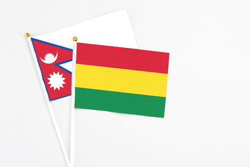 Bolivia and Nepal stick flags on white background. High quality fabric, miniature national flag. Peaceful global concept.White floor for copy space.