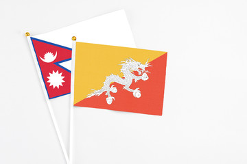 Bhutan and Nepal stick flags on white background. High quality fabric, miniature national flag. Peaceful global concept.White floor for copy space.