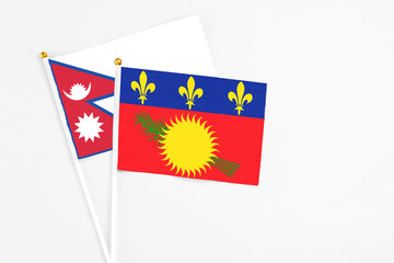 Guadeloupe and Nepal stick flags on white background. High quality fabric, miniature national flag. Peaceful global concept.White floor for copy space.