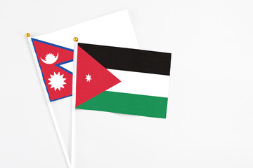 Jordan and Nepal stick flags on white background. High quality fabric, miniature national flag. Peaceful global concept.White floor for copy space.