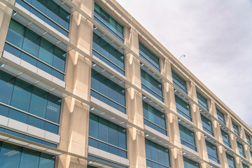 Modern building facade close up with glass windows and sunlit concrete wall