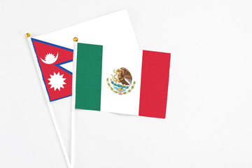 Mexico and Nepal stick flags on white background. High quality fabric, miniature national flag. Peaceful global concept.White floor for copy space.