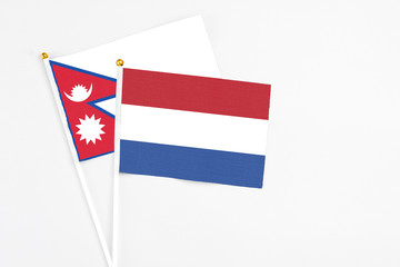 Netherlands and Nepal stick flags on white background. High quality fabric, miniature national flag. Peaceful global concept.White floor for copy space.