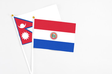 Paraguay and Nepal stick flags on white background. High quality fabric, miniature national flag. Peaceful global concept.White floor for copy space.