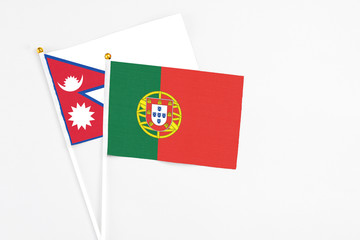 Portugal and Nepal stick flags on white background. High quality fabric, miniature national flag. Peaceful global concept.White floor for copy space.