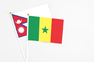 Senegal and Nepal stick flags on white background. High quality fabric, miniature national flag. Peaceful global concept.White floor for copy space.