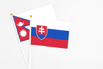 Slovakia and Nepal stick flags on white background. High quality fabric, miniature national flag. Peaceful global concept.White floor for copy space.