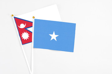 Somalia and Nepal stick flags on white background. High quality fabric, miniature national flag. Peaceful global concept.White floor for copy space.