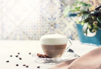 Cappuccino or latte in a glass cup on a light background.