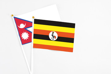 Uganda and Nepal stick flags on white background. High quality fabric, miniature national flag. Peaceful global concept.White floor for copy space.