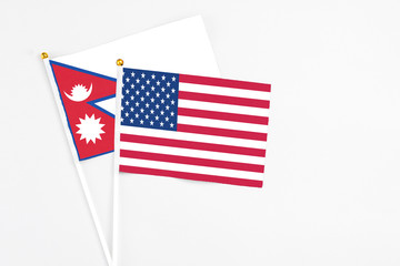 United States and Nepal stick flags on white background. High quality fabric, miniature national flag. Peaceful global concept.White floor for copy space.