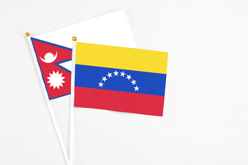 Venezuela and Nepal stick flags on white background. High quality fabric, miniature national flag. Peaceful global concept.White floor for copy space.