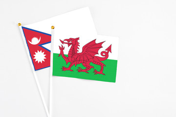 Wales and Nepal stick flags on white background. High quality fabric, miniature national flag. Peaceful global concept.White floor for copy space.
