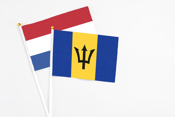 Barbados and Netherlands stick flags on white background. High quality fabric, miniature national flag. Peaceful global concept.White floor for copy space.