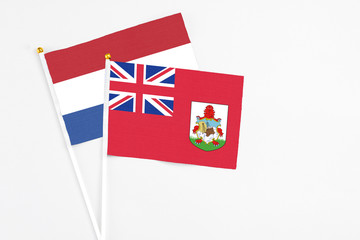 Fototapeta premium Bermuda and Netherlands stick flags on white background. High quality fabric, miniature national flag. Peaceful global concept.White floor for copy space.