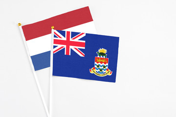 Fototapeta premium Cayman Islands and Netherlands stick flags on white background. High quality fabric, miniature national flag. Peaceful global concept.White floor for copy space.