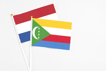 Comoros and Netherlands stick flags on white background. High quality fabric, miniature national flag. Peaceful global concept.White floor for copy space.
