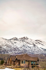 Beautiful house with balcony and view of a snowy mountain against cloudy sky