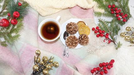 Christmas or New Year background with fir branches, lemon and tea on the background of Christmas decorations, a warm woolen sweater, flat lay, top view, selective focus. 