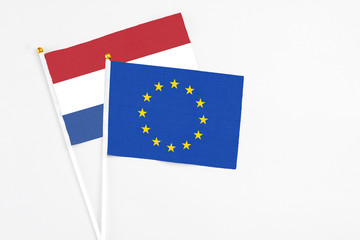 European Union and Netherlands stick flags on white background. High quality fabric, miniature national flag. Peaceful global concept.White floor for copy space.
