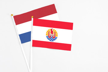 French Polynesia and Netherlands stick flags on white background. High quality fabric, miniature national flag. Peaceful global concept.White floor for copy space.