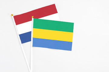 Gabon and Netherlands stick flags on white background. High quality fabric, miniature national flag. Peaceful global concept.White floor for copy space.
