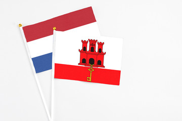 Gibraltar and Netherlands stick flags on white background. High quality fabric, miniature national flag. Peaceful global concept.White floor for copy space.