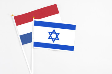 Israel and Netherlands stick flags on white background. High quality fabric, miniature national flag. Peaceful global concept.White floor for copy space.