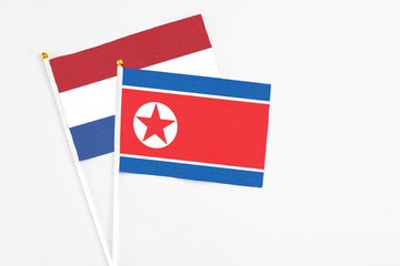North Korea and Netherlands stick flags on white background. High quality fabric, miniature national flag. Peaceful global concept.White floor for copy space.