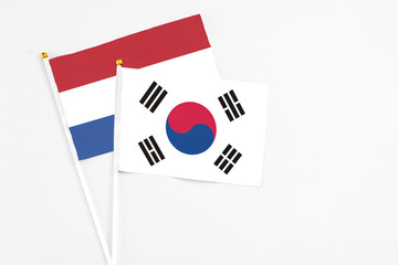 South Korea and Netherlands stick flags on white background. High quality fabric, miniature national flag. Peaceful global concept.White floor for copy space.