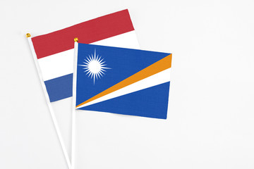 Marshall Islands and Netherlands stick flags on white background. High quality fabric, miniature national flag. Peaceful global concept.White floor for copy space.