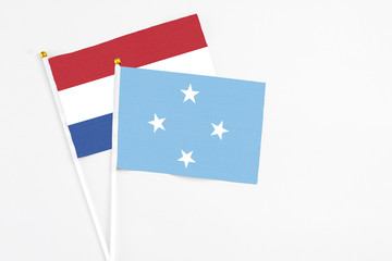 Micronesia and Netherlands stick flags on white background. High quality fabric, miniature national flag. Peaceful global concept.White floor for copy space.