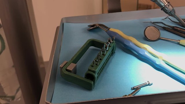 Close up shot of a set of dental drills bits sitting next to a dental mirrors on a tablet
