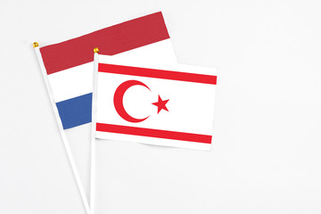 Northern Cyprus and Netherlands stick flags on white background. High quality fabric, miniature national flag. Peaceful global concept.White floor for copy space.