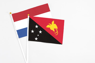 Papua New Guinea and Netherlands stick flags on white background. High quality fabric, miniature national flag. Peaceful global concept.White floor for copy space.