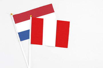 Peru and Netherlands stick flags on white background. High quality fabric, miniature national flag. Peaceful global concept.White floor for copy space.