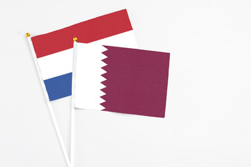 Qatar and Netherlands stick flags on white background. High quality fabric, miniature national flag. Peaceful global concept.White floor for copy space.