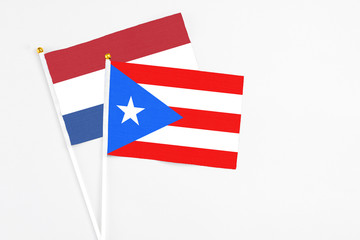 Fototapeta premium Puerto Rico and Netherlands stick flags on white background. High quality fabric, miniature national flag. Peaceful global concept.White floor for copy space.