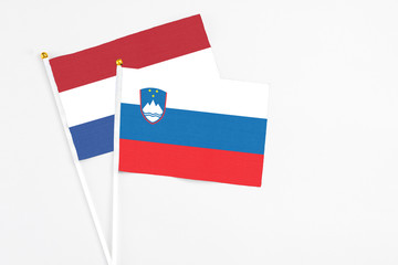 Slovenia and Netherlands stick flags on white background. High quality fabric, miniature national flag. Peaceful global concept.White floor for copy space.