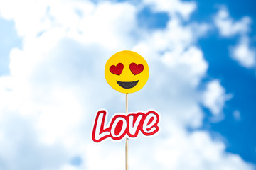 KYIV, UKRAINE - MAY 25, 2019: paper cut heart eyes emoji and love word