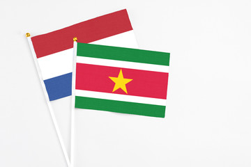 Suriname and Netherlands stick flags on white background. High quality fabric, miniature national flag. Peaceful global concept.White floor for copy space.