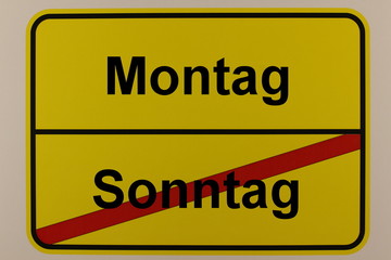Grafische Darstellung der Wochentage Sonntag und Montag auf einem Ortsschild