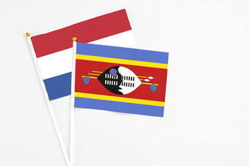 Swaziland and Netherlands stick flags on white background. High quality fabric, miniature national flag. Peaceful global concept.White floor for copy space.